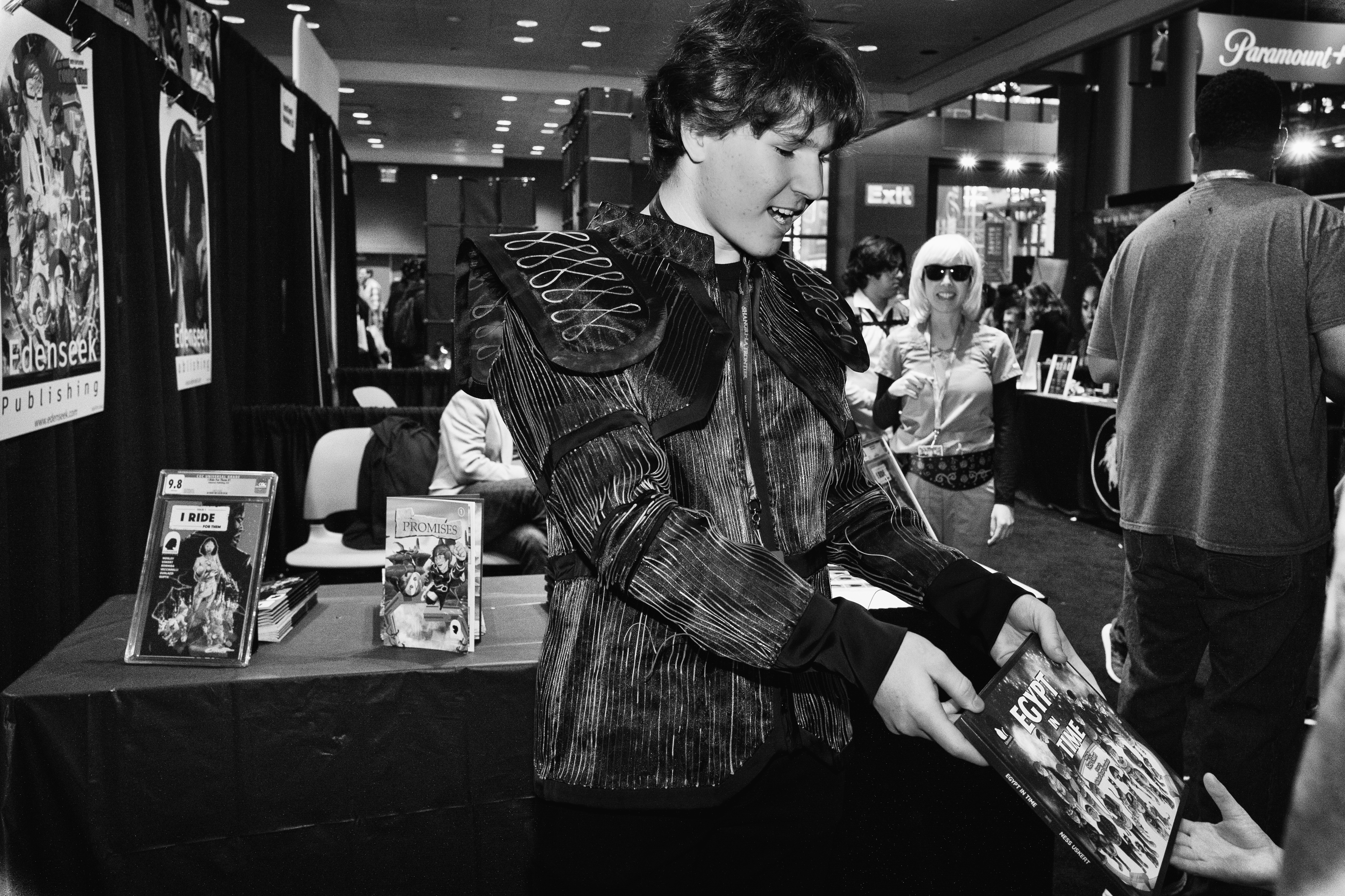Handing a copy of the picture book Egypt in Time across the Edenseek Publishing booth table to a visitor